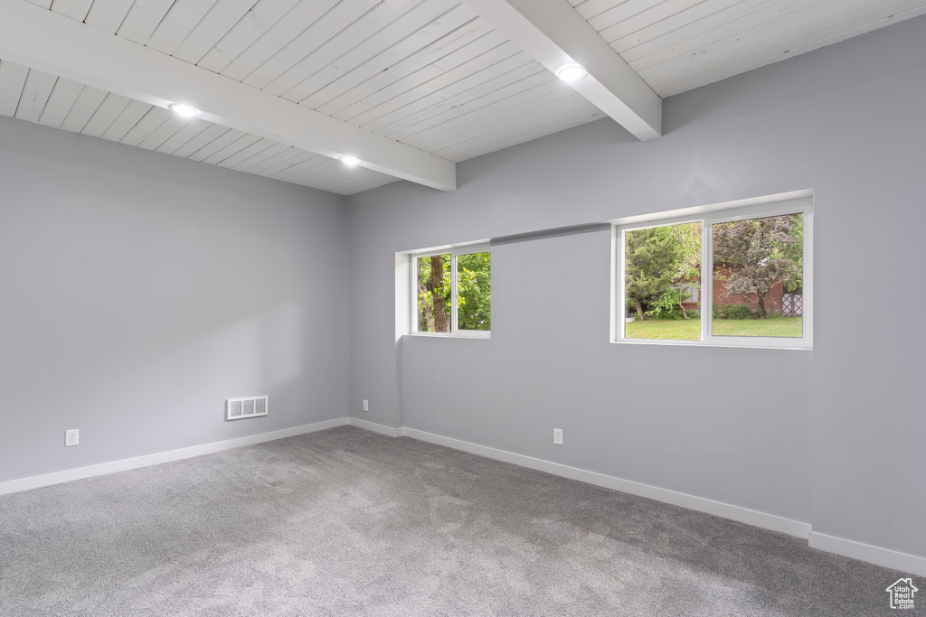 Empty room featuring baseboards, carpet floors, and wooden ceiling with exposed beams