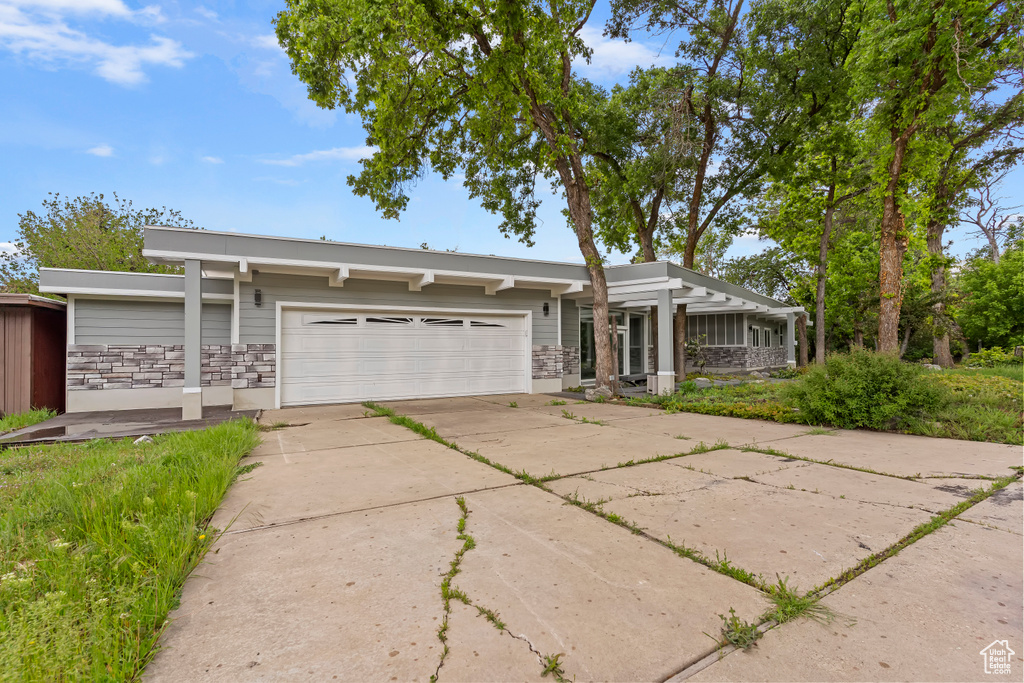 Mid-century inspired home with a garage, concrete driveway, and stone siding