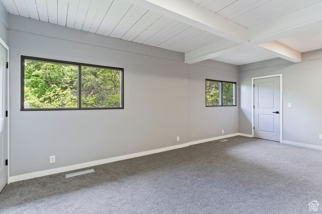 Spare room featuring carpet, baseboards, and beam ceiling