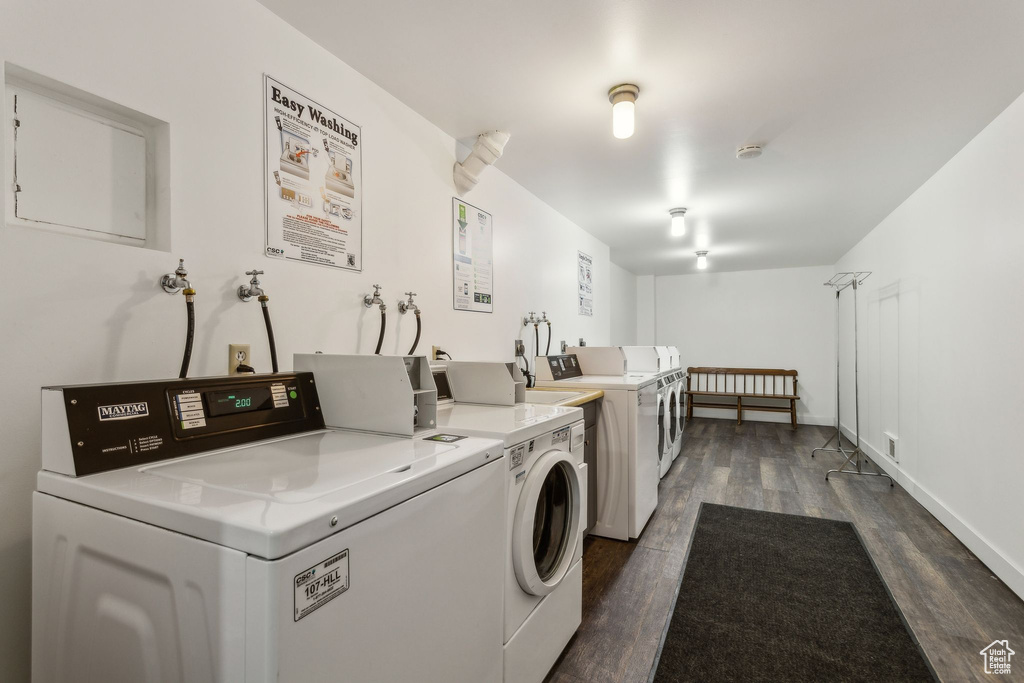 Community laundry with separate washer and dryer and dark wood-style floors