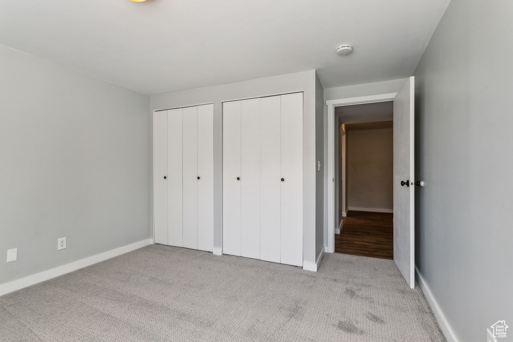 Unfurnished bedroom with two closets, carpet floors, and baseboards