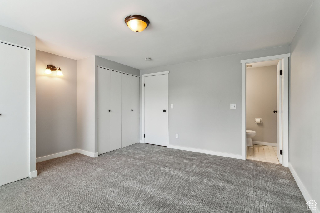 Unfurnished bedroom with carpet, baseboards, and ensuite bathroom