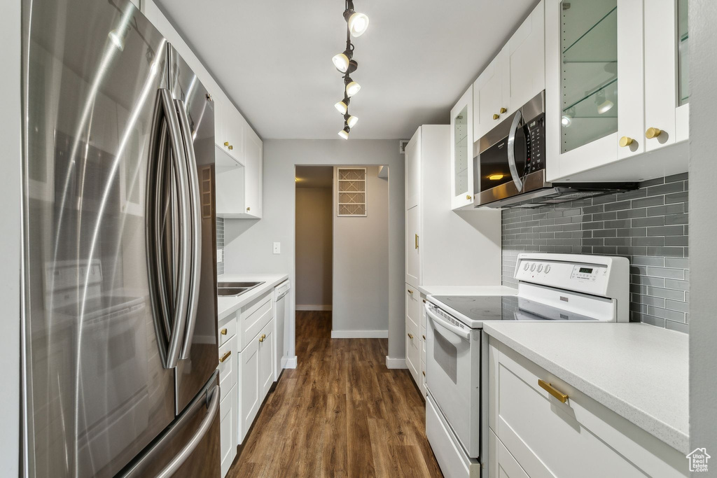 Kitchen featuring stainless steel appliances, backsplash, light countertops, and white cabinets