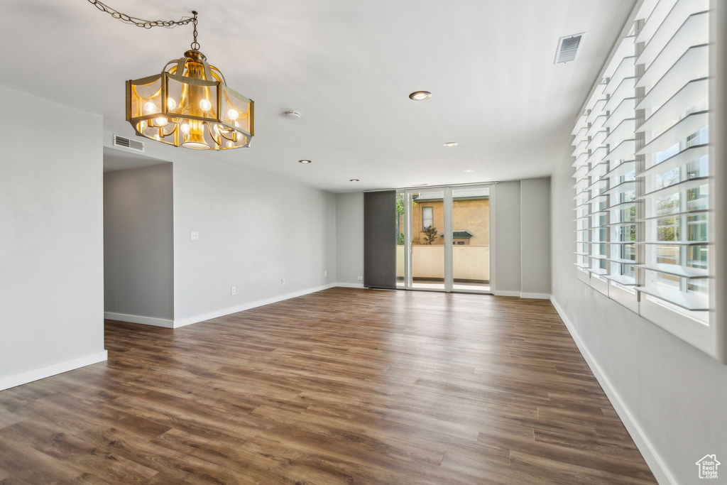 Spare room with a chandelier, dark wood-type flooring, recessed lighting, and baseboards