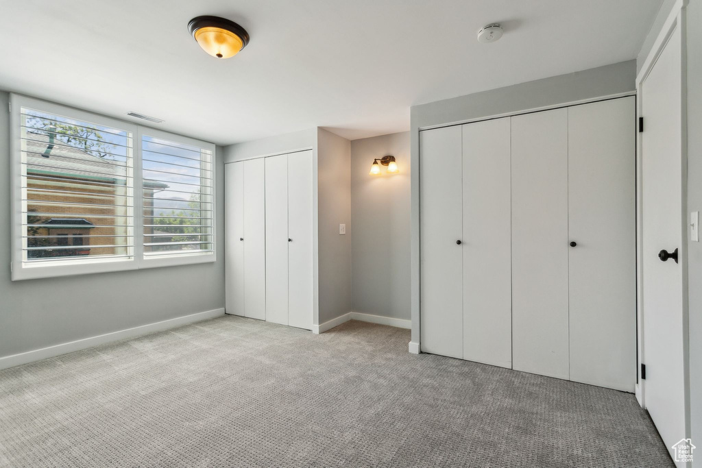 Unfurnished bedroom with multiple closets, carpet floors, and baseboards