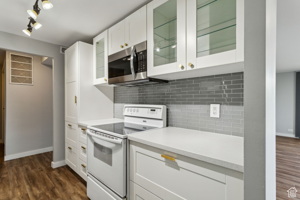 Kitchen featuring electric range, stainless steel microwave, light countertops, white cabinets, and tasteful backsplash