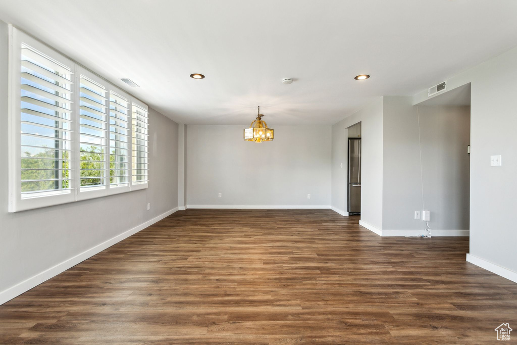 Empty room with a chandelier, recessed lighting, baseboards, dark wood-style flooring, and a smoke detector