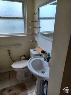 Bathroom with healthy amount of natural light, toilet, tile patterned floors, and a sink