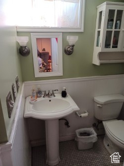 Bathroom featuring toilet, a wainscoted wall, and tile patterned floors