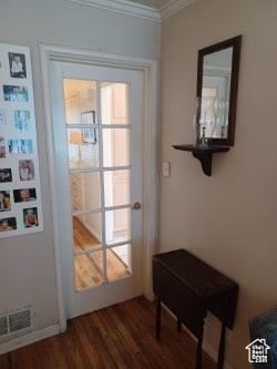 Doorway to outside featuring ornamental molding and dark wood-type flooring