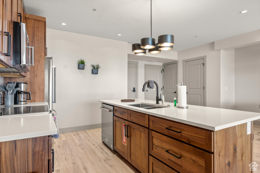 Kitchen featuring a sink, brown cabinets, light wood-style flooring, baseboards, and light countertops