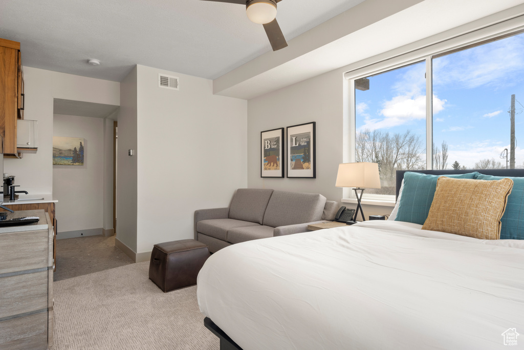 Bedroom featuring light colored carpet, ceiling fan, and baseboards