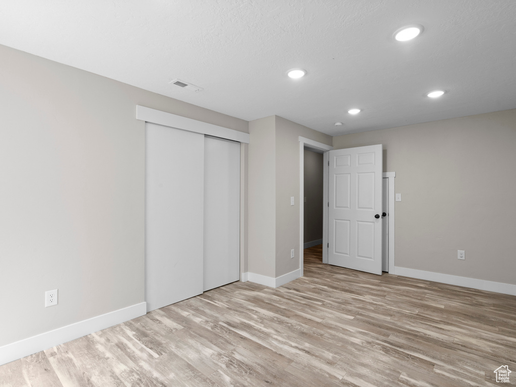 Unfurnished bedroom with wood finished floors, baseboards, recessed lighting, and a closet