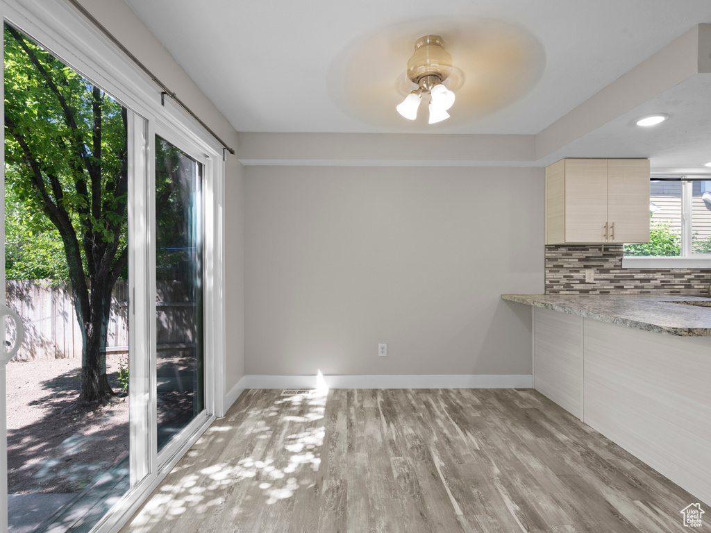 Unfurnished dining area featuring light wood-type flooring, ceiling fan, and baseboards