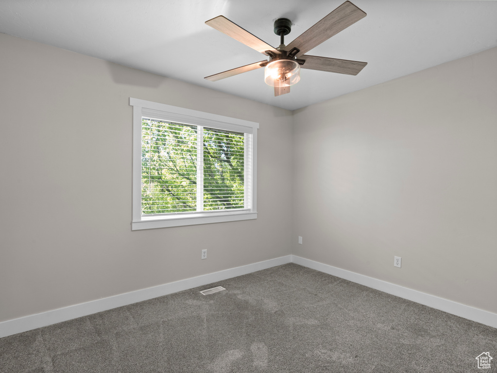 Empty room featuring a ceiling fan, baseboards, and carpet