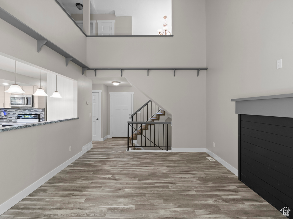 Unfurnished living room with wood finished floors, stairs, baseboards, and a chandelier