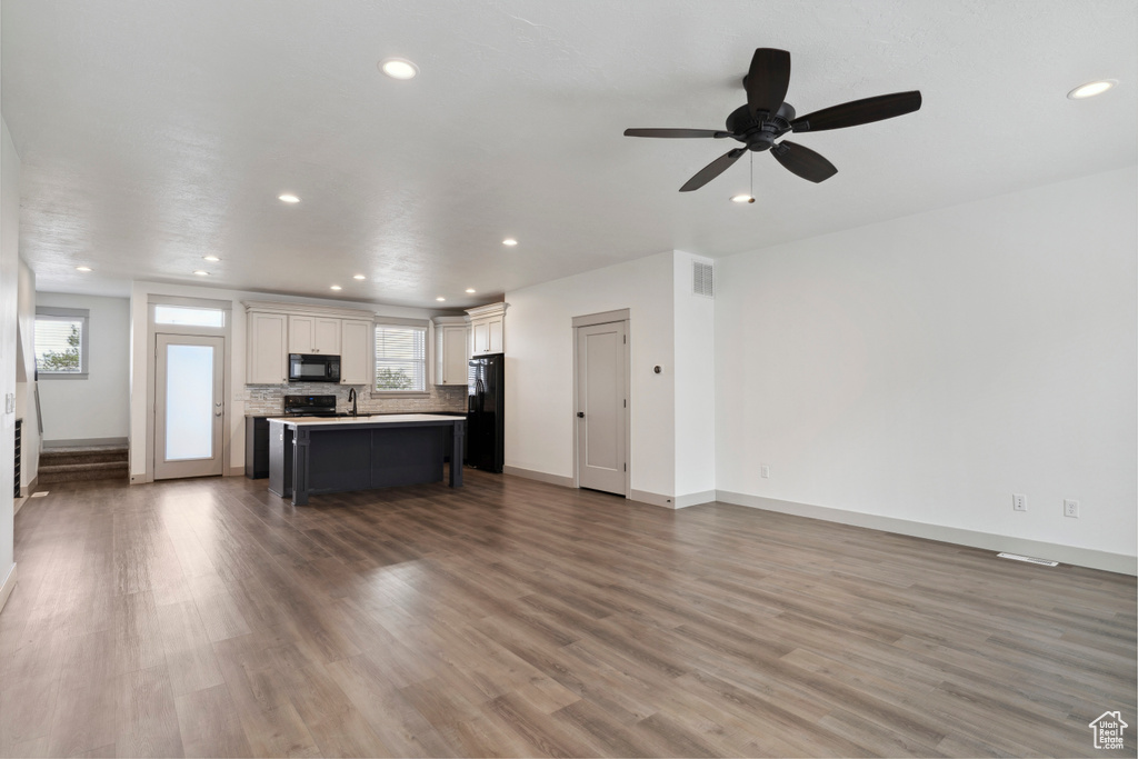 Living room with healthy amount of natural light, recessed lighting, wood finished floors, baseboards, and a ceiling fan
