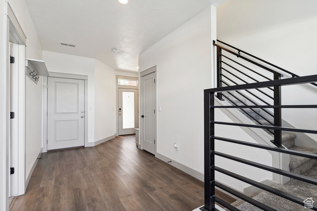 Foyer with wood finished floors, baseboards, and stairway
