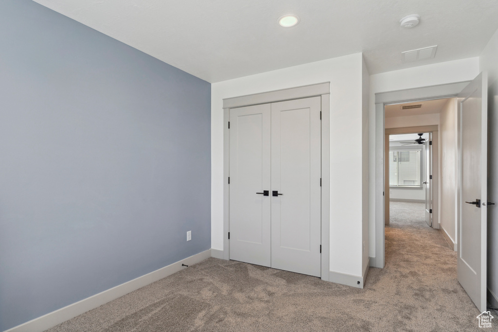 Unfurnished bedroom featuring light colored carpet, baseboards, a closet, and recessed lighting