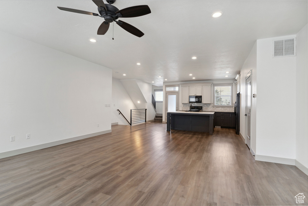 Living room featuring recessed lighting, light wood-type flooring, baseboards, ceiling fan, and stairway