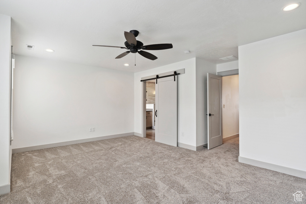 Unfurnished bedroom with carpet flooring, a barn door, recessed lighting, baseboards, and a ceiling fan