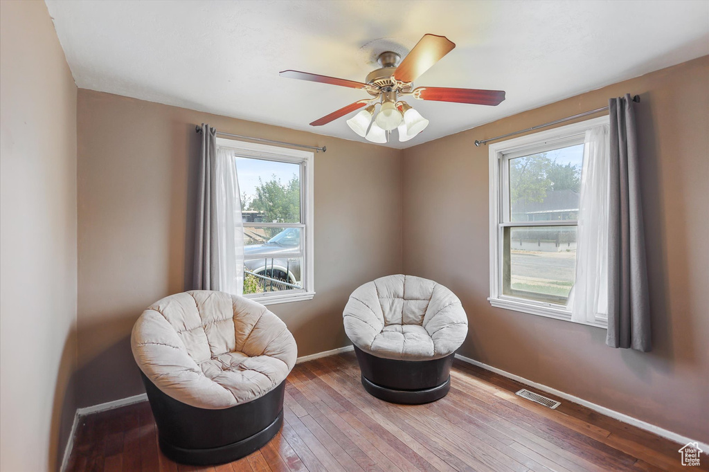 Living area featuring healthy amount of natural light, wood-type flooring, baseboards, and ceiling fan