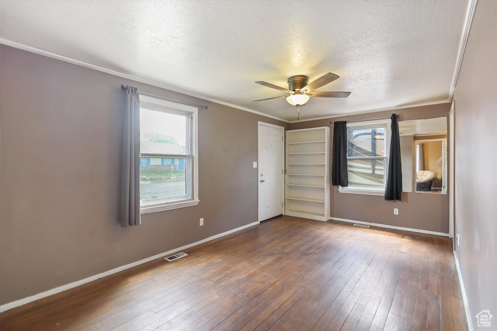 Spare room with a textured ceiling, ceiling fan, crown molding, hardwood / wood-style floors, and baseboards