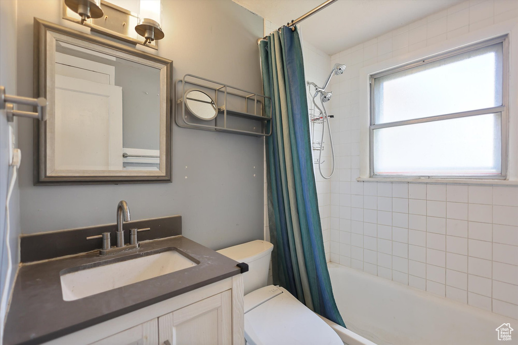Bathroom with toilet, shower / tub combo, and vanity
