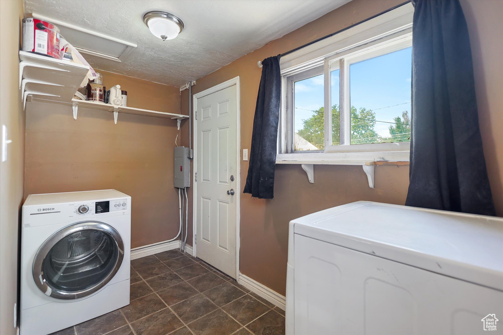 Laundry area featuring washer and dryer, baseboards, dark tile patterned floors, attic access, and a textured ceiling