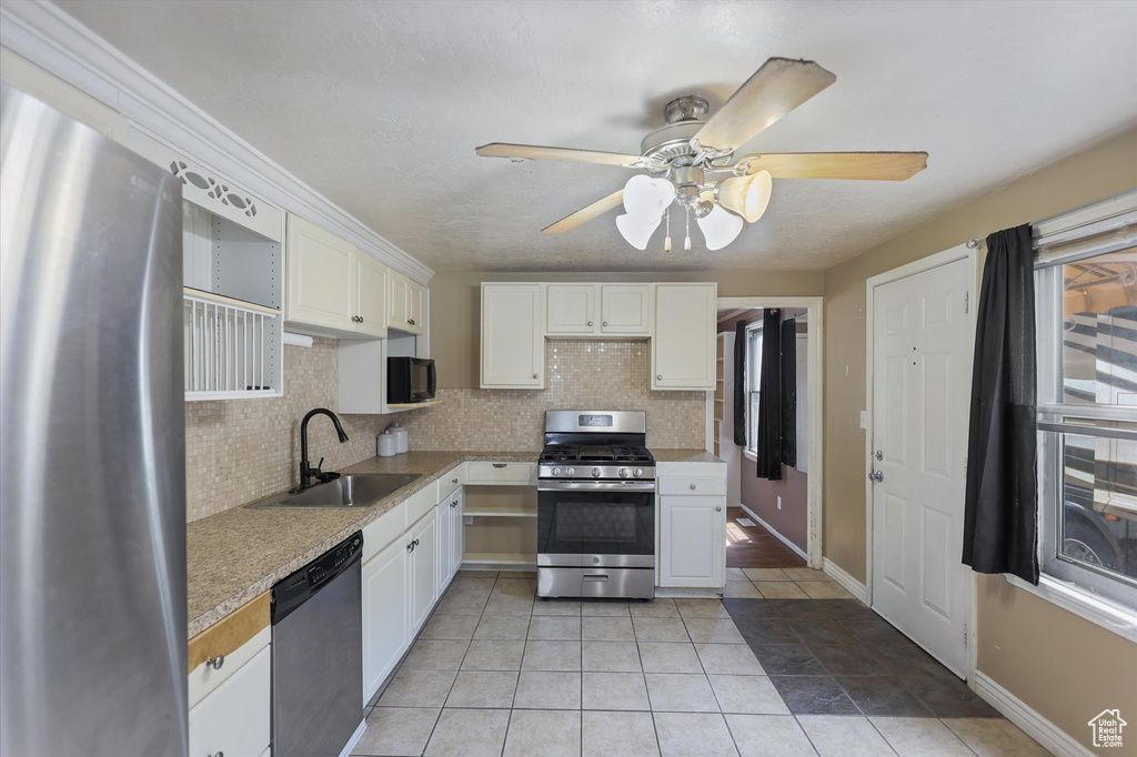 Kitchen with stainless steel appliances, a sink, tasteful backsplash, and white cabinetry