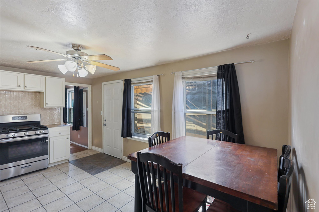Dining room featuring light tile patterned floors, a ceiling fan, a textured ceiling, and baseboards