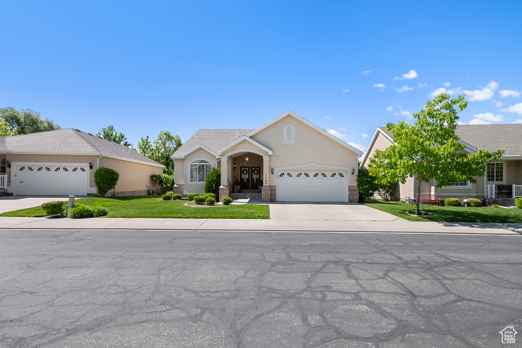 View of front of house featuring a garage, concrete driveway, stucco siding, and a front lawn