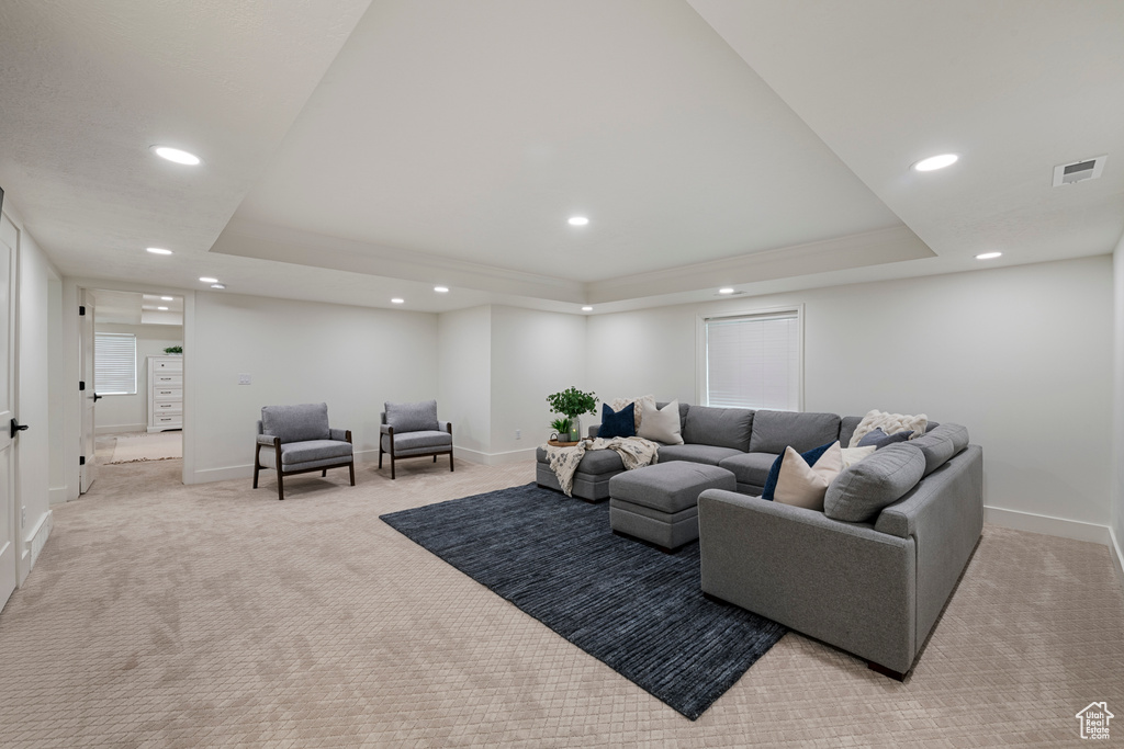 Living area featuring a tray ceiling, light colored carpet, recessed lighting, and baseboards