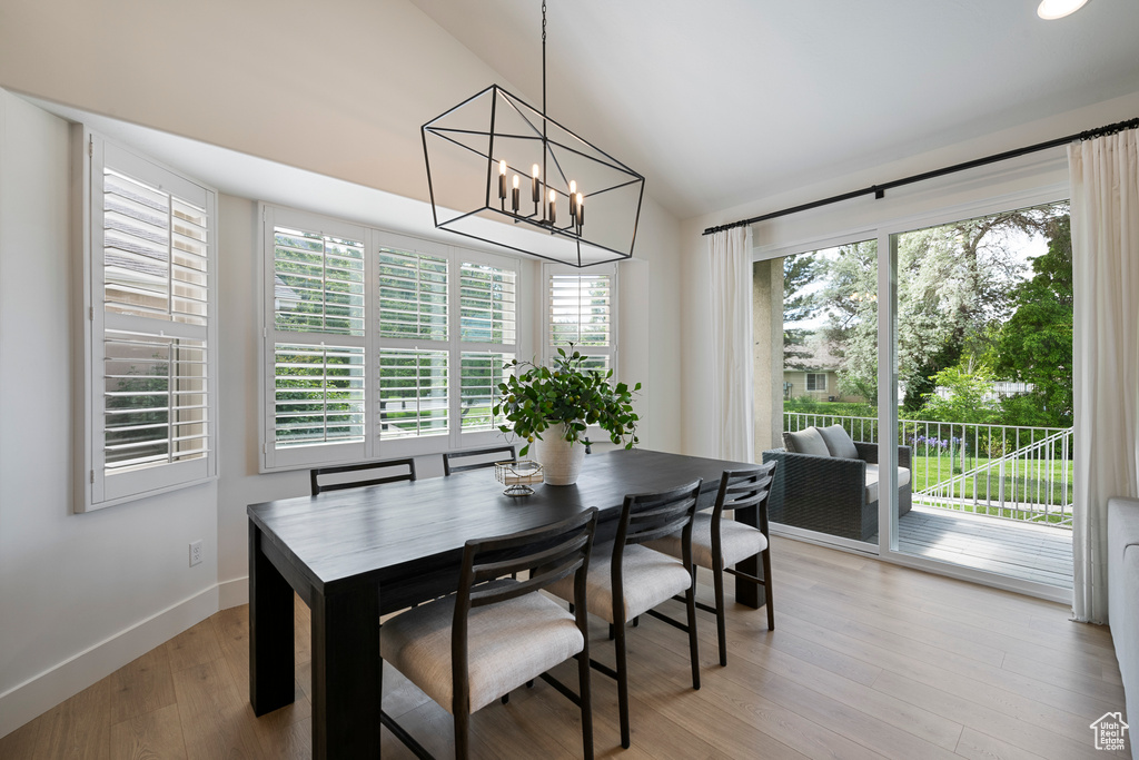 Dining area featuring a chandelier, light wood-style floors, baseboards, and high vaulted ceiling