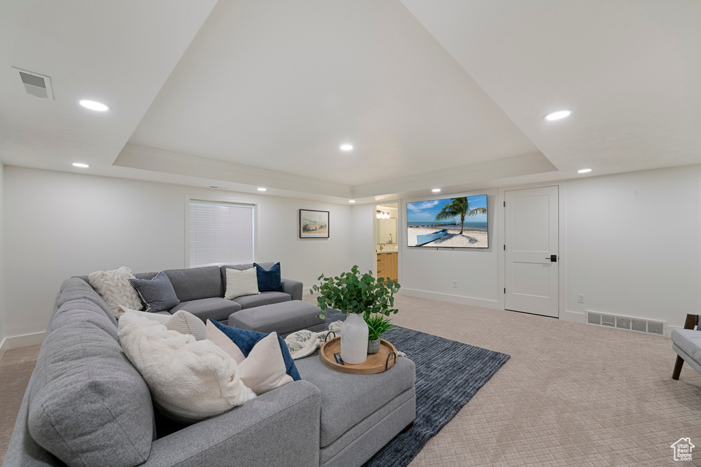 Carpeted living area with a raised ceiling, recessed lighting, and baseboards