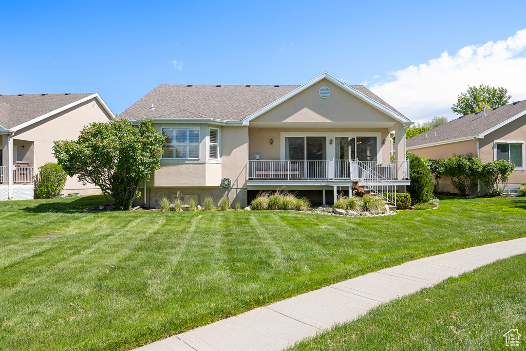 View of front of property featuring stucco siding, a front lawn, and roof with shingles