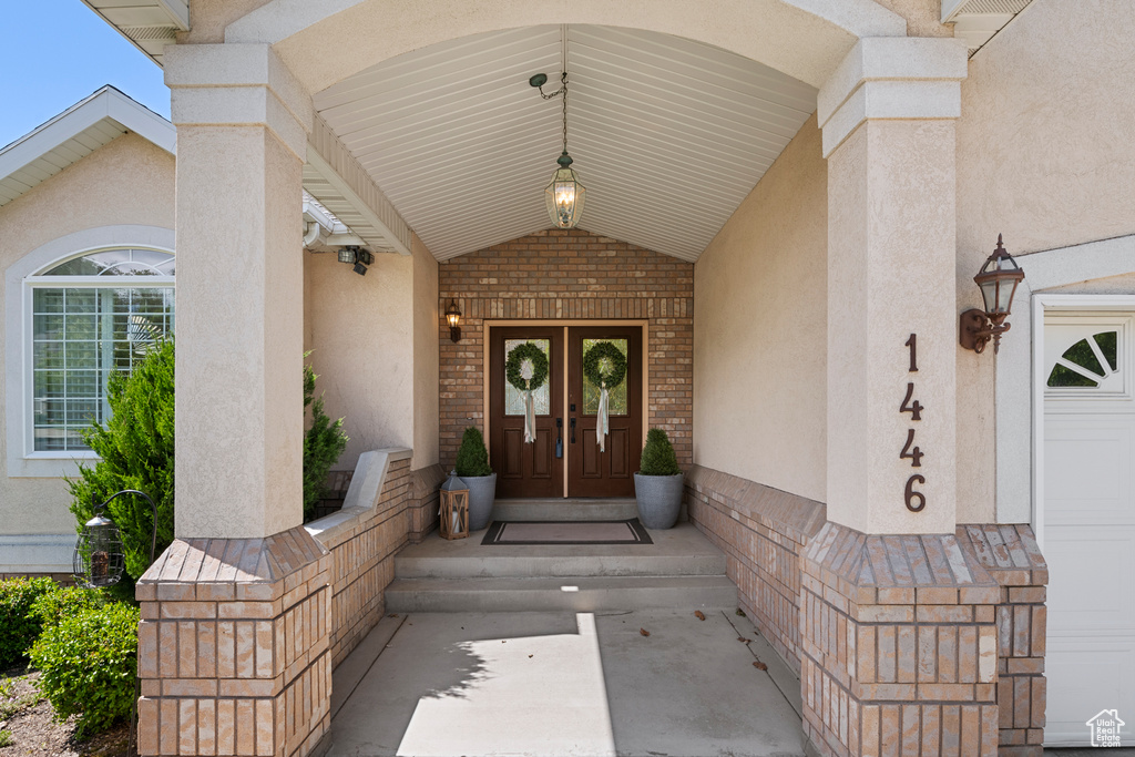 Property entrance featuring stucco siding, french doors, and brick siding