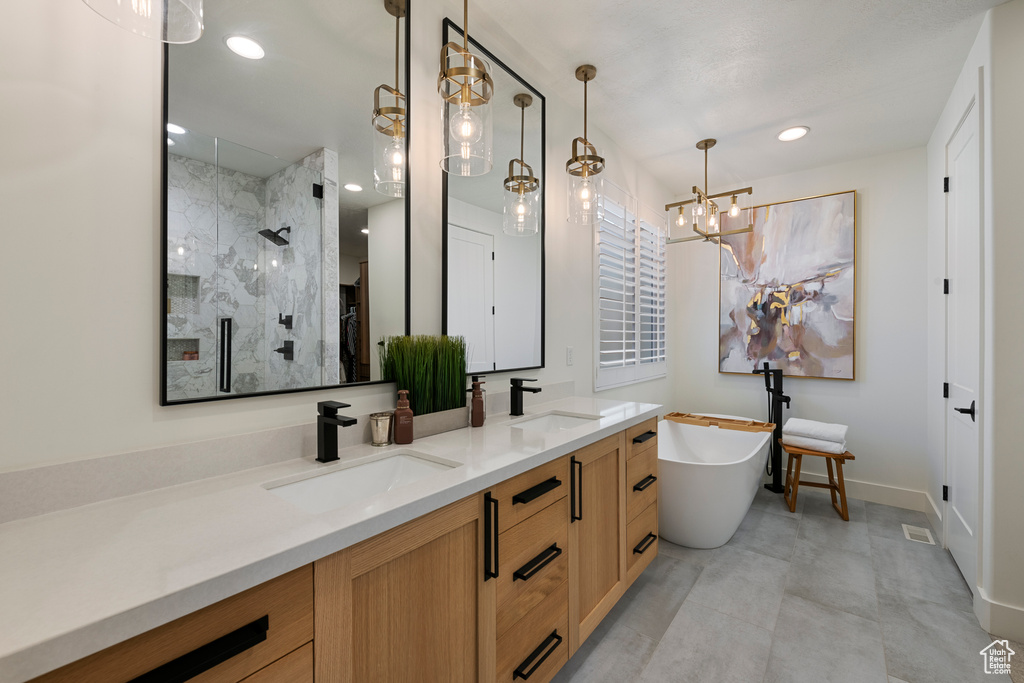 Full bath with a walk in shower, double vanity, a freestanding bath, baseboards, and recessed lighting