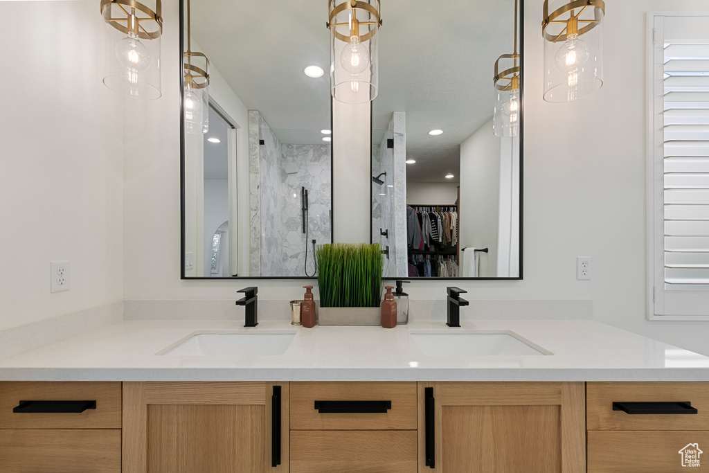 Full bath with double vanity, a shower with shower door, a spacious closet, and recessed lighting