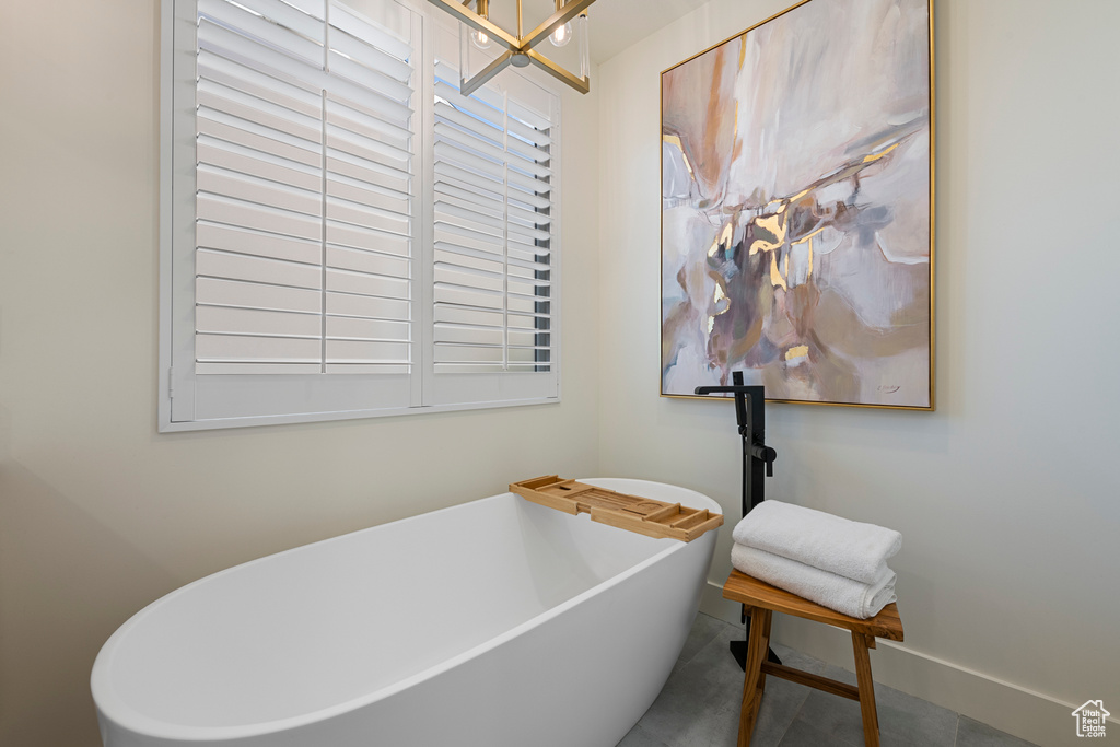 Full bath with a soaking tub, baseboards, and a chandelier