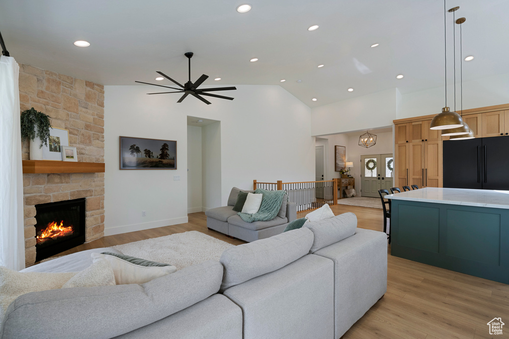 Living area with high vaulted ceiling, light wood-style floors, a ceiling fan, a fireplace, and recessed lighting