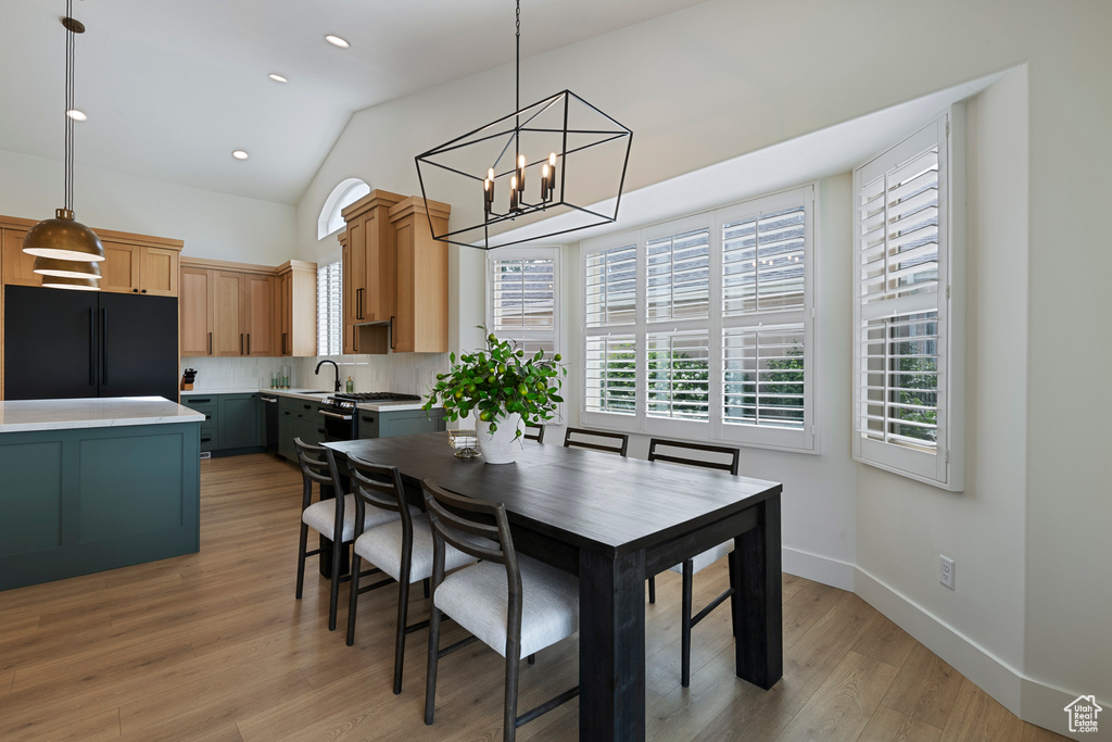 Dining room featuring a chandelier, vaulted ceiling, light wood-type flooring, recessed lighting, and baseboards
