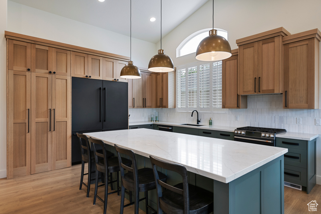 Kitchen with black refrigerator, backsplash, a sink, light stone counters, and a center island