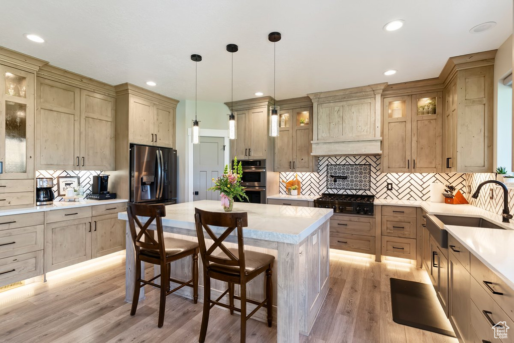 Kitchen featuring a sink, stainless steel double oven, refrigerator with ice dispenser, decorative backsplash, and light countertops
