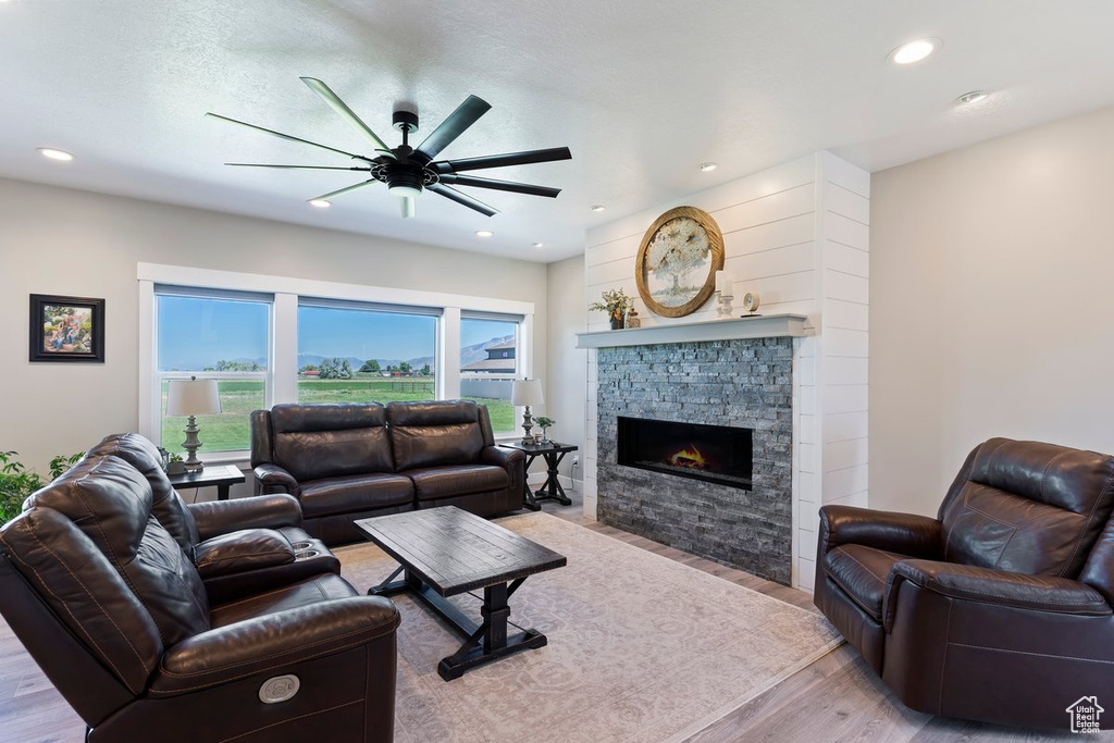 Living area featuring light wood-style floors, ceiling fan, a fireplace, and recessed lighting