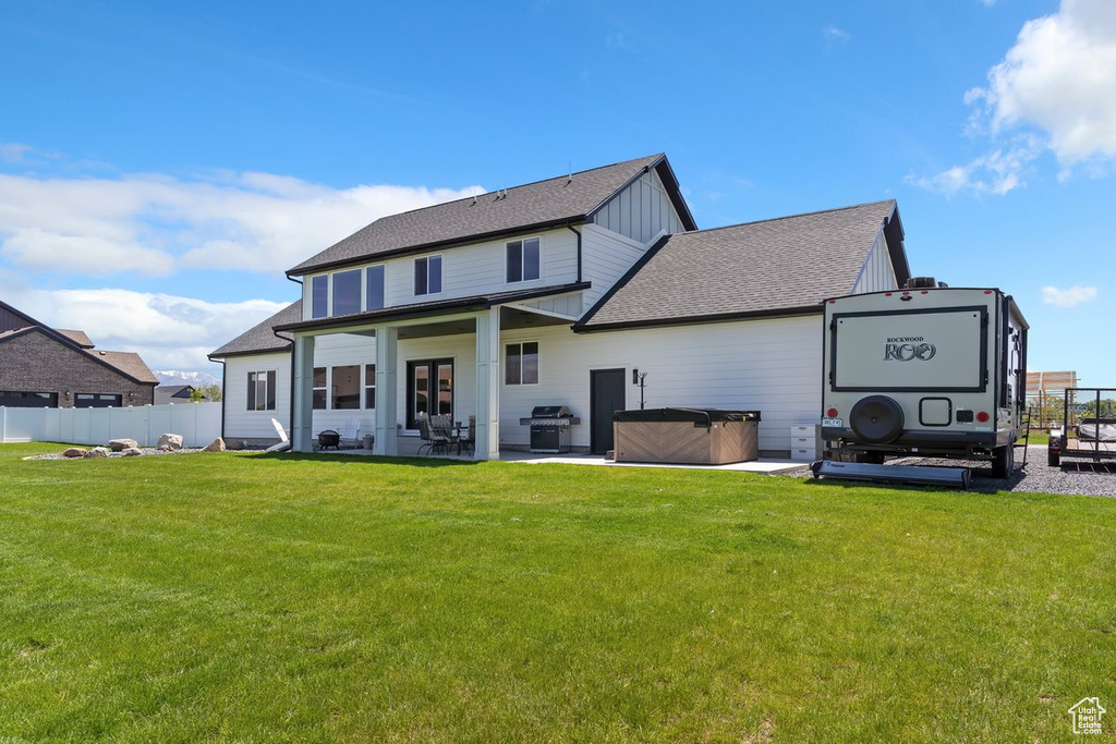 Back of property featuring a hot tub, board and batten siding, a patio area, and roof with shingles