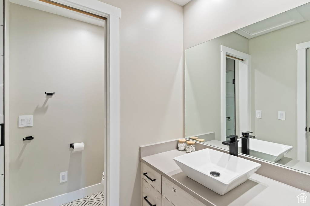 Bathroom featuring vanity, toilet, and baseboards