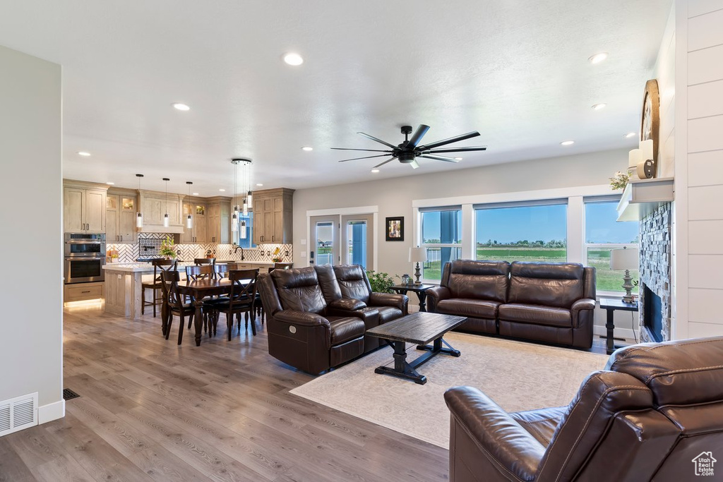Living room featuring light wood-style floors, recessed lighting, a ceiling fan, and a fireplace