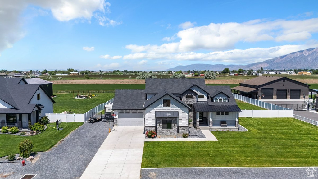 View of front of home featuring concrete driveway, stone siding, a standing seam roof, a mountain view, and metal roof