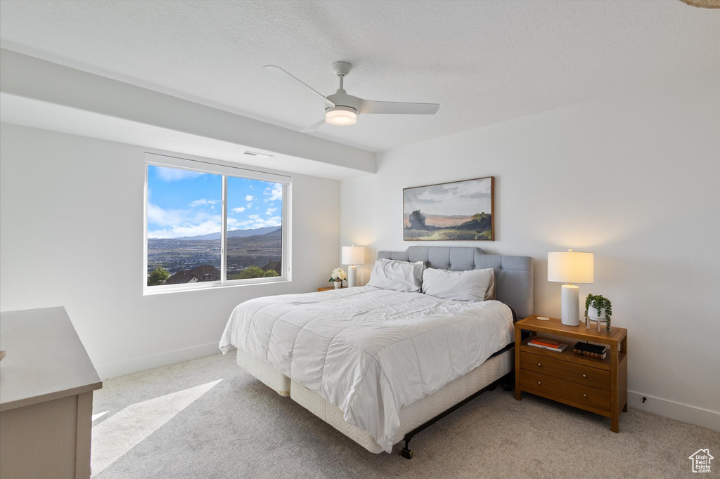 Bedroom with light colored carpet, baseboards, and ceiling fan